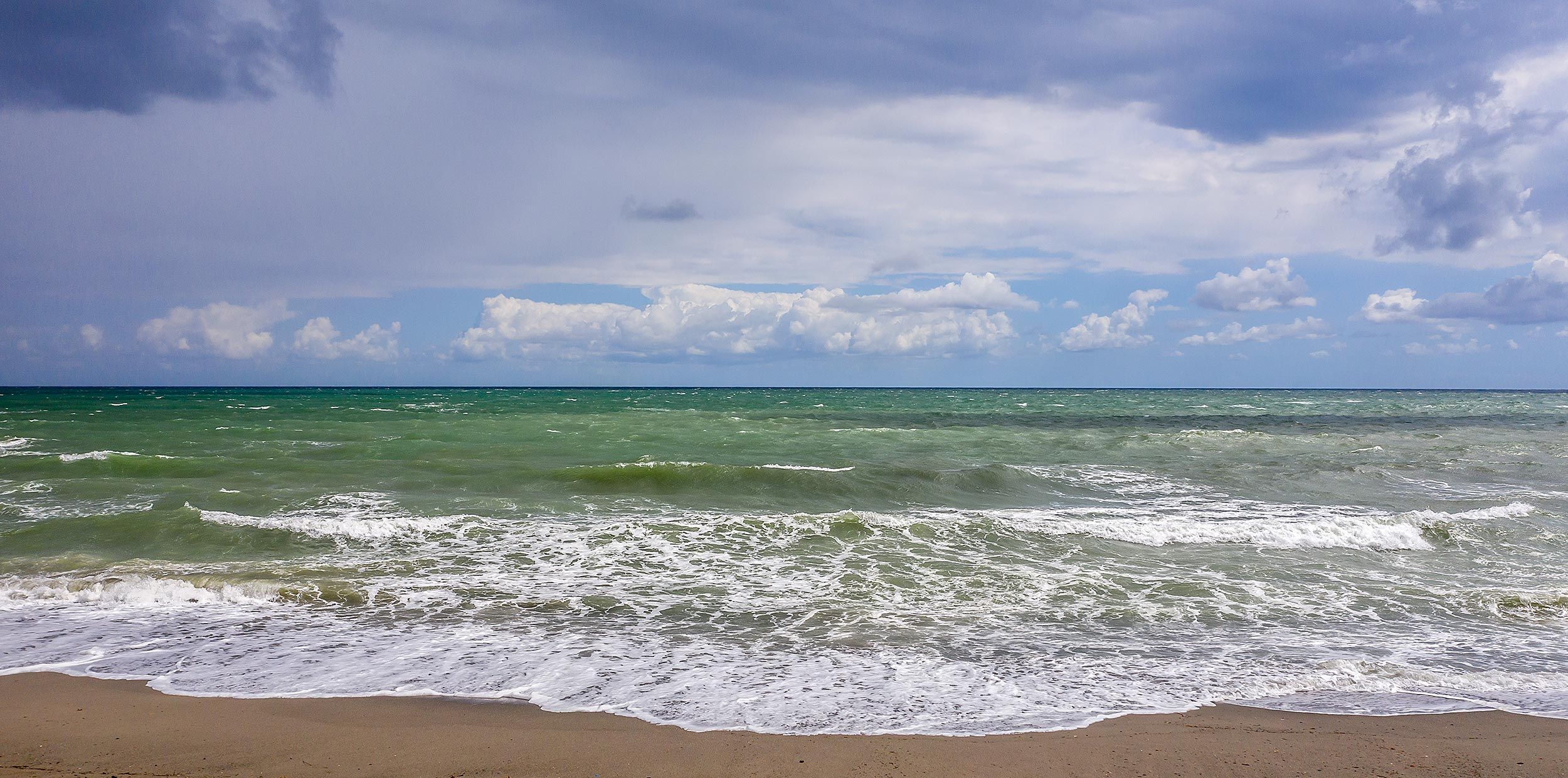 Wellen am Strand unter Wolken