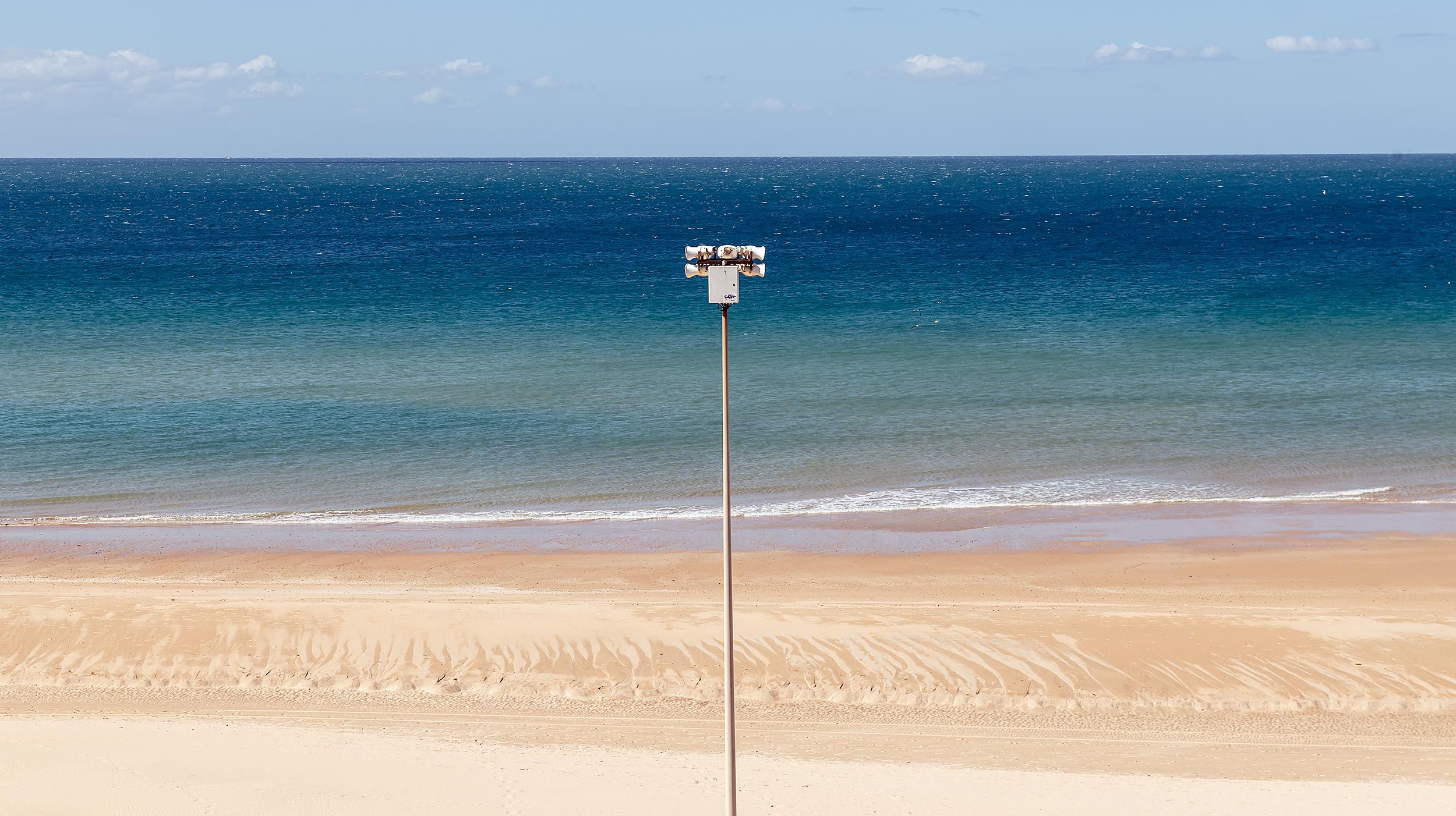 Sandstrand mit Laterne vor blauem Meer
